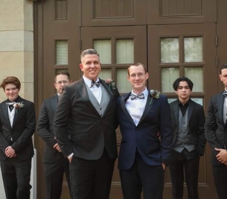 Todd and Jurgy standing together at a wedding